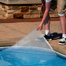 Blue Wave clear solar blanket being lifted from pool water