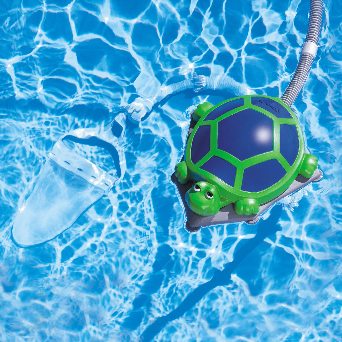 Polaris Turbo Turtle floating in a pool with hose and underwater debris bag visible
